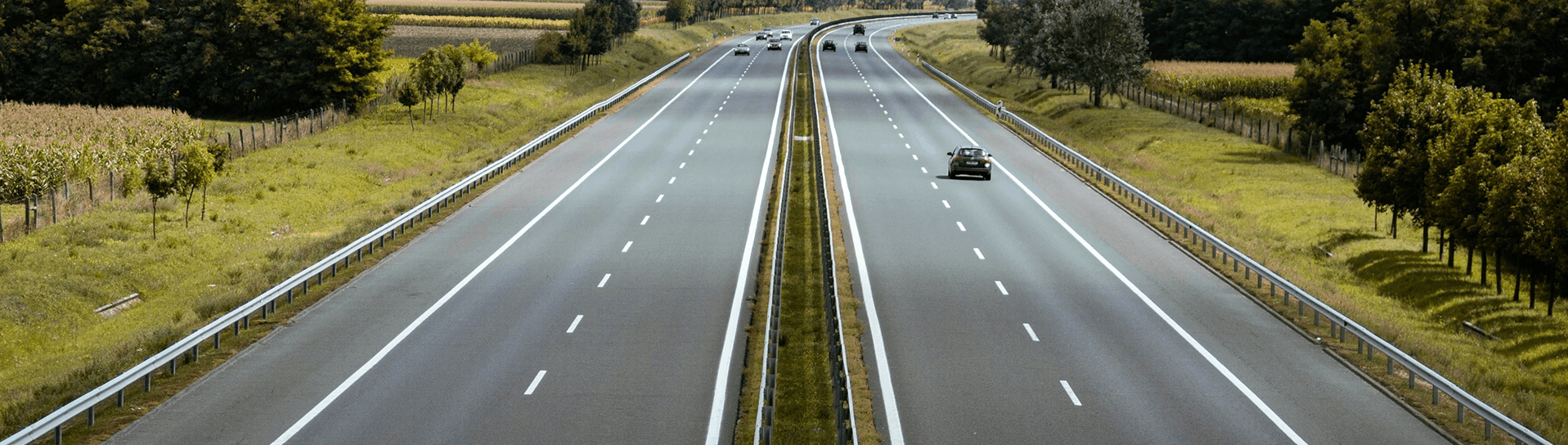 Pregledna autocesta s dva kolnika okružena zelenilom.